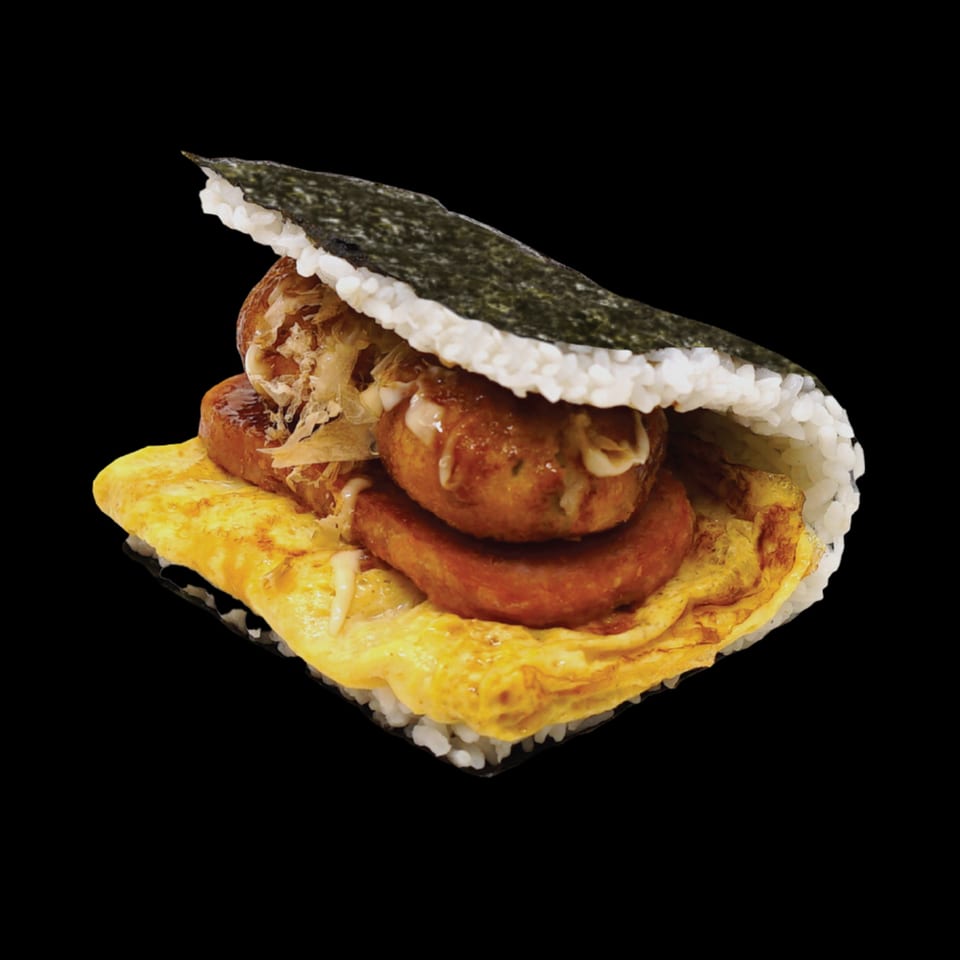 Okinawa onigiri with rice, nori, omelet, spam, and takoyaki, drizzled with sauce.